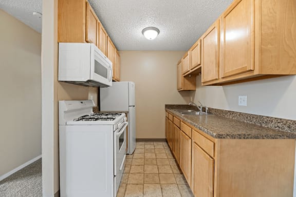 A kitchen with white appliances and wooden cabinets.