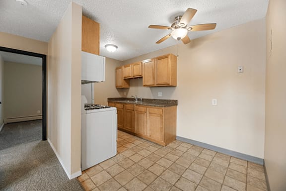 A kitchen area with a refrigerator, cabinets, and a ceiling fan.