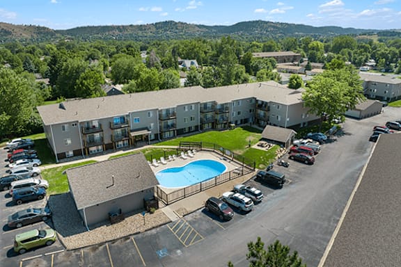 A large apartment complex with a swimming pool and a parking lot.