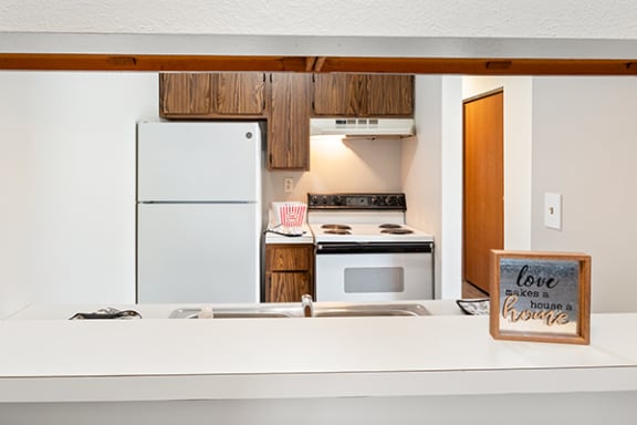 a kitchen with a white refrigerator and stove and a sign on the counter