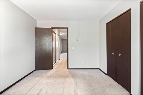 an empty room with a closet and a door to a hallway