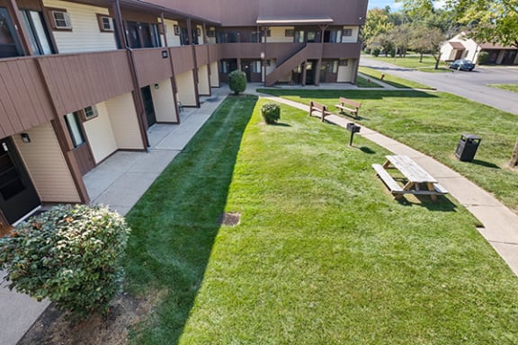 a view of the outside of a building with a lawn and benches