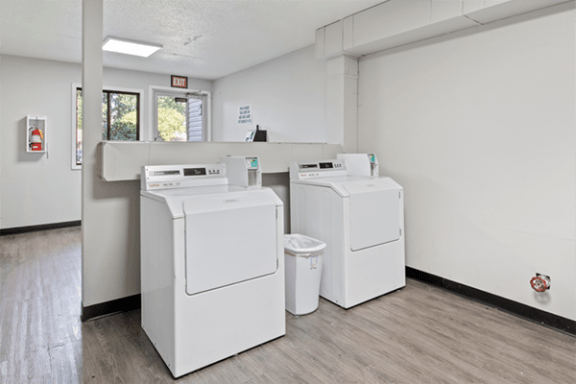two washers and two washing machines in an empty laundry room