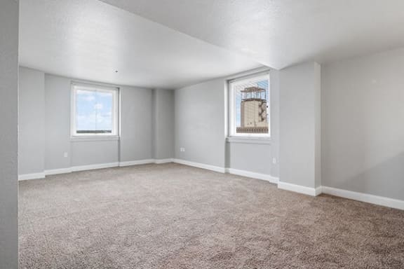 an empty living room with carpet and two windows