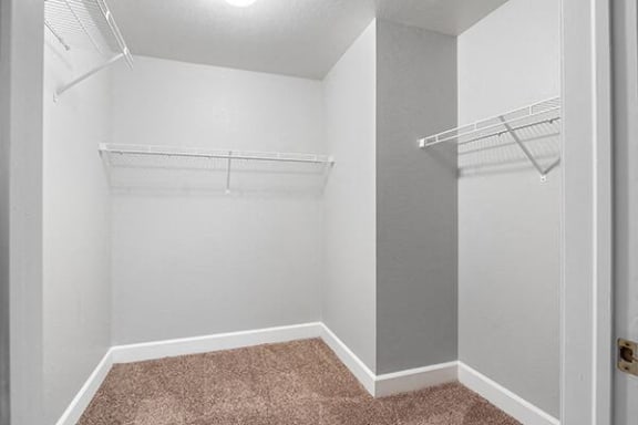 an empty closet with a white wall and an empty shelves