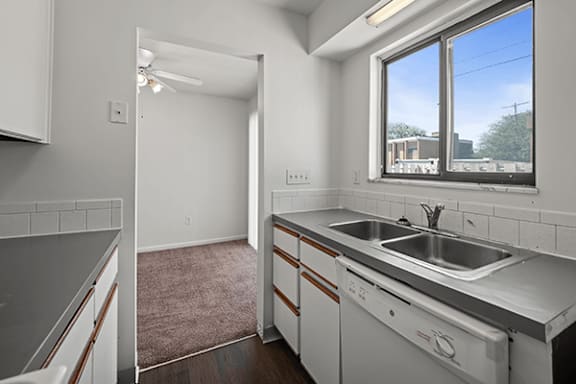 A kitchen with white cabinets and a window overlooking a street.