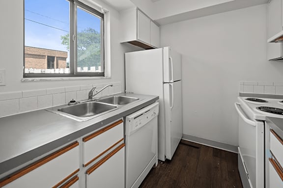 A kitchen with white appliances and a window.