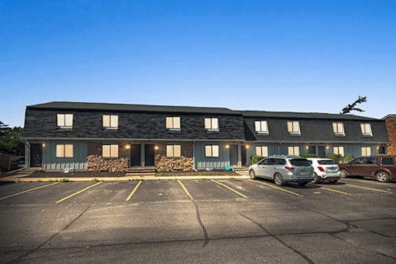 A parking lot in front of a building with cars parked.