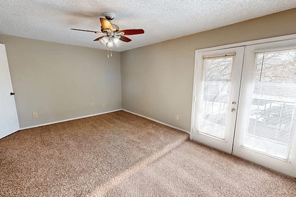 A room with a ceiling fan and carpeted floor.
