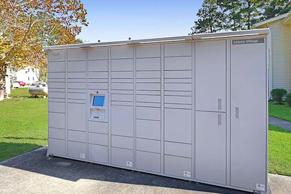A large white storage unit with a digital display and a sign that reads "Colony Village.".