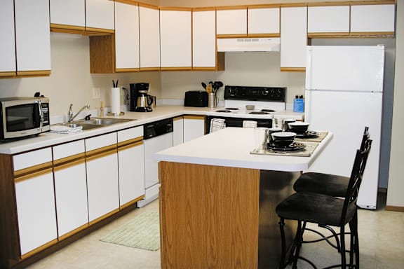 A kitchen with white cabinets and a white refrigerator.