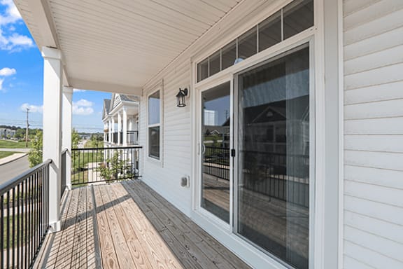 A white house with a deck and sliding glass doors.