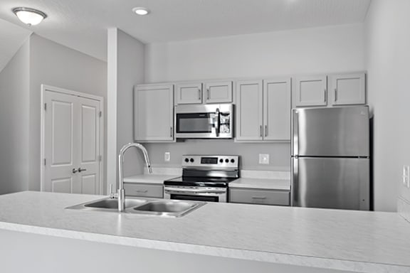 A kitchen with a stainless steel refrigerator, microwave, oven, and sink.