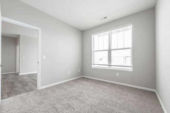 a bedroom with a large window and a carpeted floor