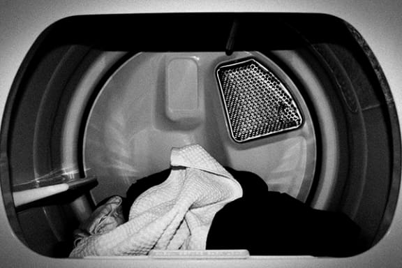 a person laying down in a dryer with a towel