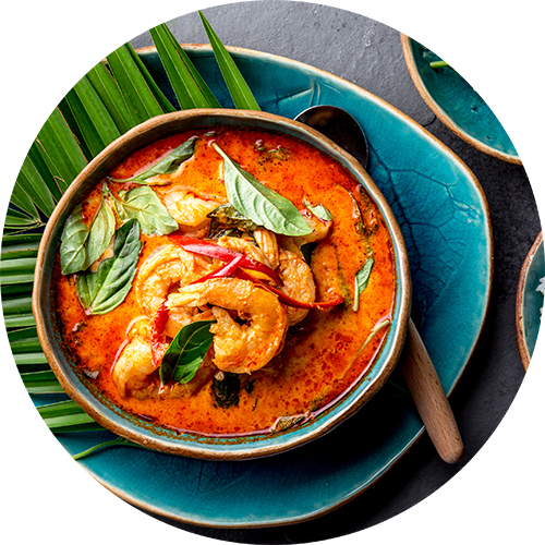 A bowl of shrimp curry with a spoon on a blue plate.