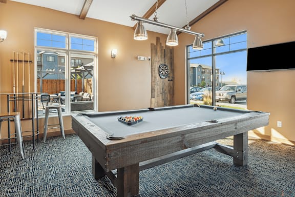 A pool table in a room with a view of the parking lot outside.