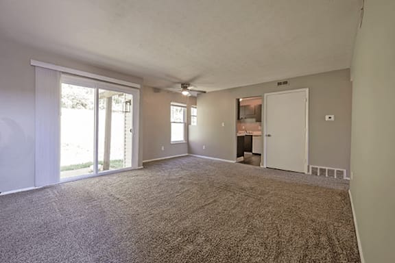 A spacious room with carpeted floor and sliding glass doors.