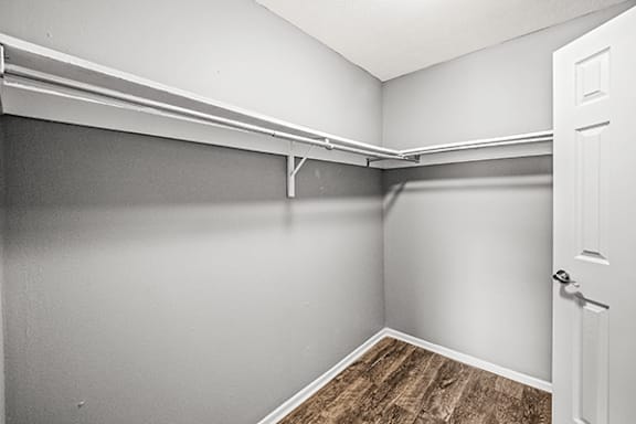 A white door is on the right side of a room with white walls and a wooden floor.