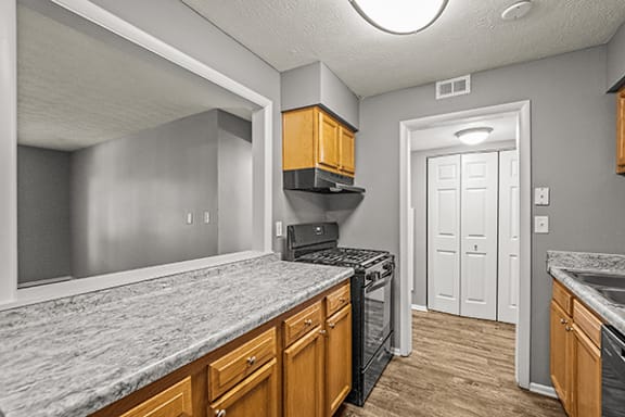 A kitchen with a marble countertop and wooden cabinets.