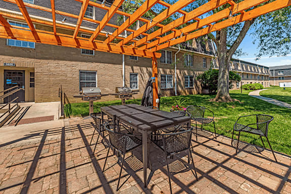 A patio with a table and chairs under an orange pergola.