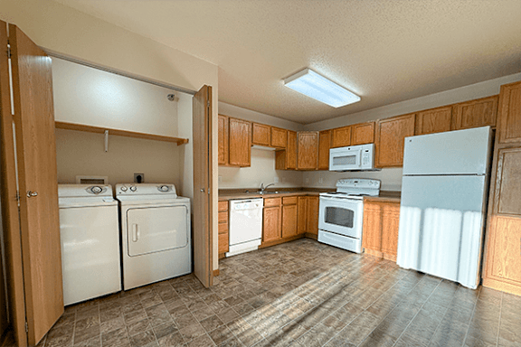 A kitchen with white appliances and wooden cabinets.