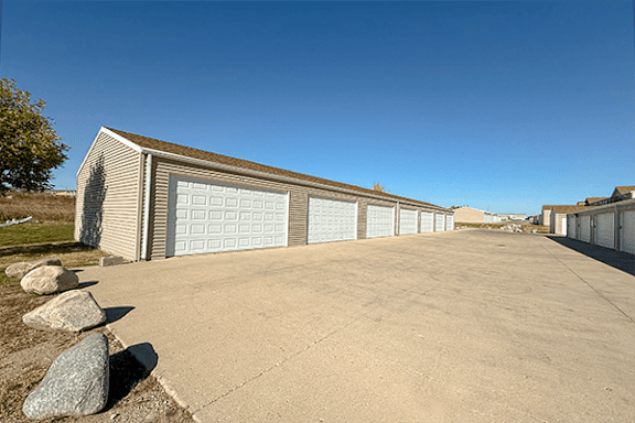 A long garage with a white door is surrounded by a concrete driveway.
