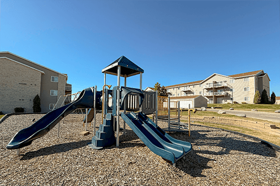 A playground with a blue slide and a wooden structure.
