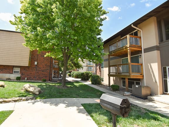 an apartment building with a tree and a grill