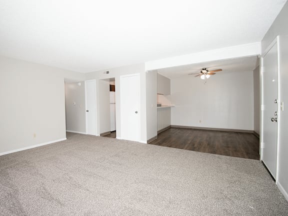 A room with a carpeted floor and a ceiling fan.