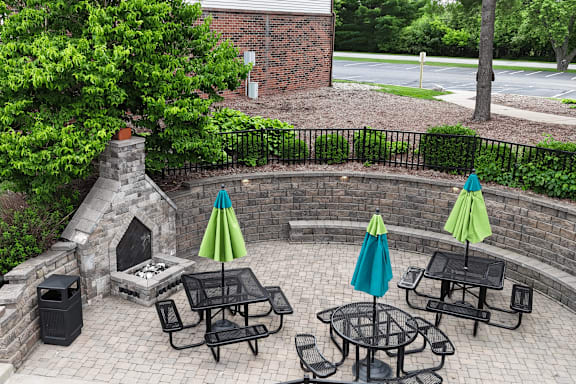 A patio with tables and chairs and umbrellas.