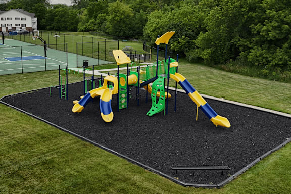 A playground with a yellow and green slide.