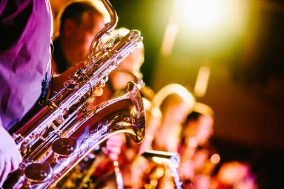 a group of people playing saxophone on a stage