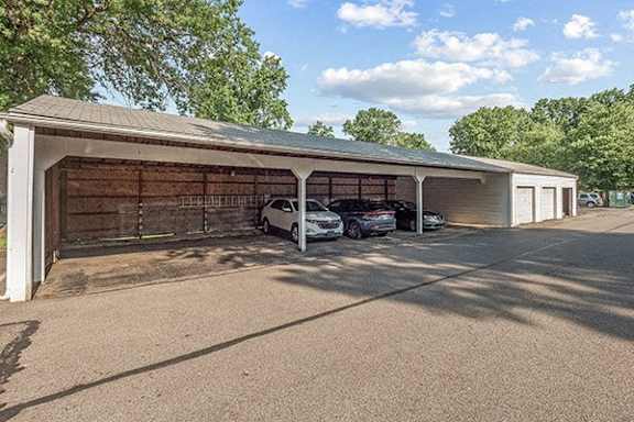 A carport with two cars parked inside.