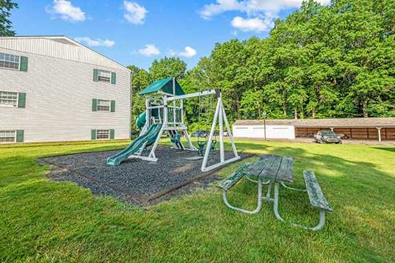 A playground with a green slide and a picnic table.
