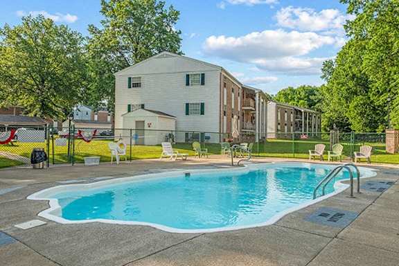 A swimming pool in front of a building surrounded by trees.