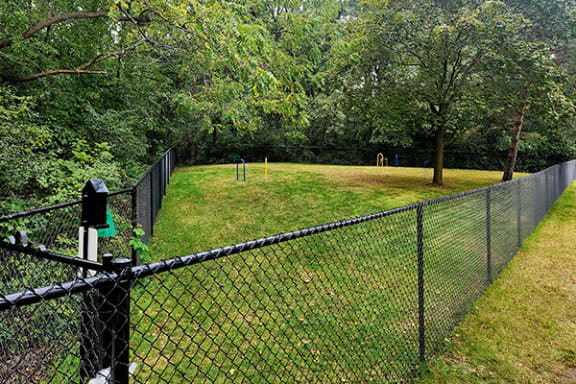 a chain link fence with a field of grass and trees
