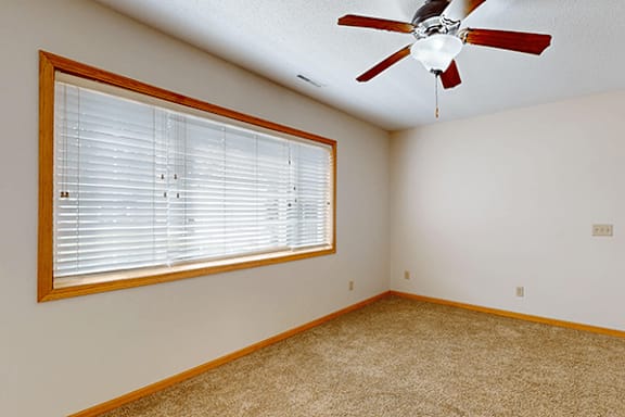 A room with a ceiling fan and a window with blinds.