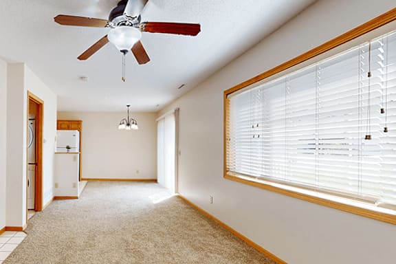 A room with a ceiling fan and a window with blinds.