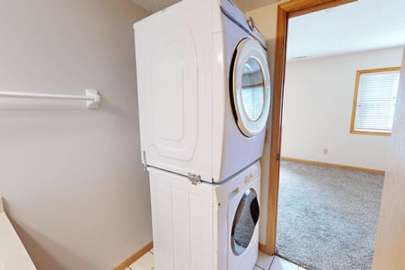 A white washing machine and dryer stacked on top of each other in a laundry room.