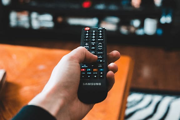 A person is holding a Samsung remote control in their hand.