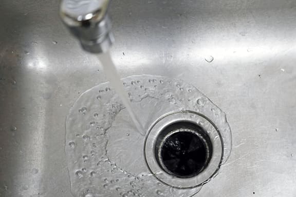 Water is flowing from a tap into a sink.