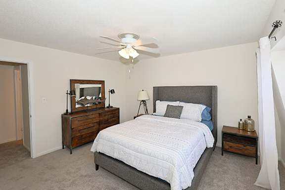 A bedroom with a bed, nightstand, and a ceiling fan.
