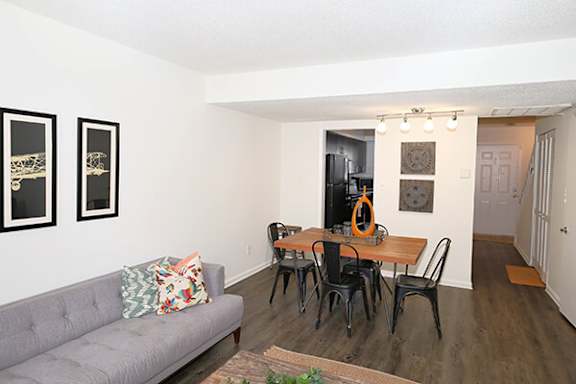 A grey couch with a pillow and a wooden table with chairs.