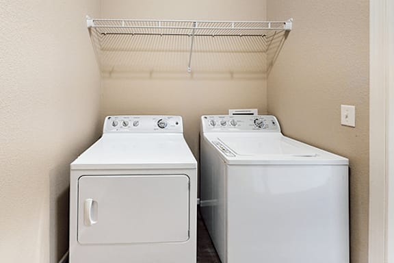 Two white front loading washing machines in a laundry room.