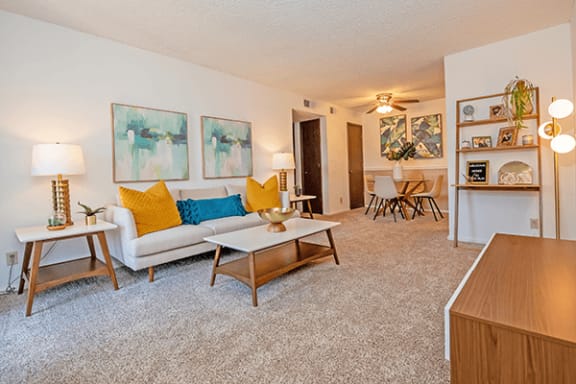 a living room with a white couch and yellow and blue pillows