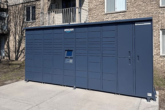 A blue Amazon storage unit is in front of a brick building.