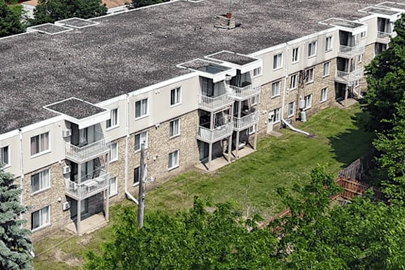 Apartment complex with balconies and trees in the foreground.