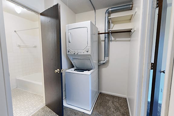 A small white washing machine is in a small room.