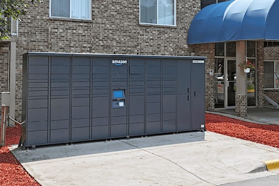 A grey Amazon storage unit sits in front of a brick building.